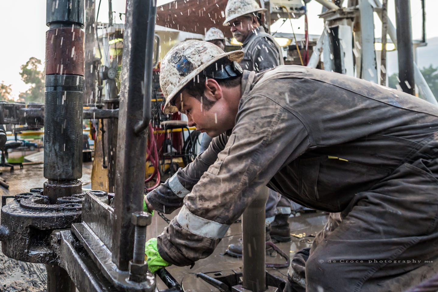 A roughneck connects drilling pipe as photographer gets sprayed.