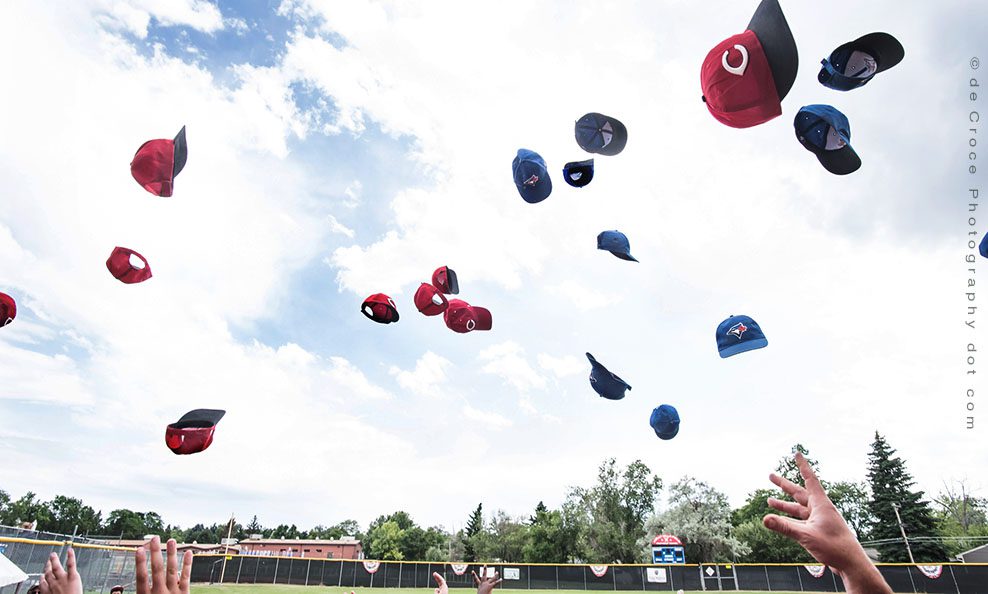 red and blue baseball caps tossed into the air
