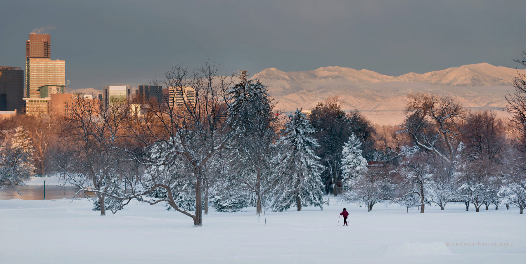 Denver Photographer captures perfect scene of Denver office towers snow covered Rocky mountains and nordic skier in park after giant March snowfall.