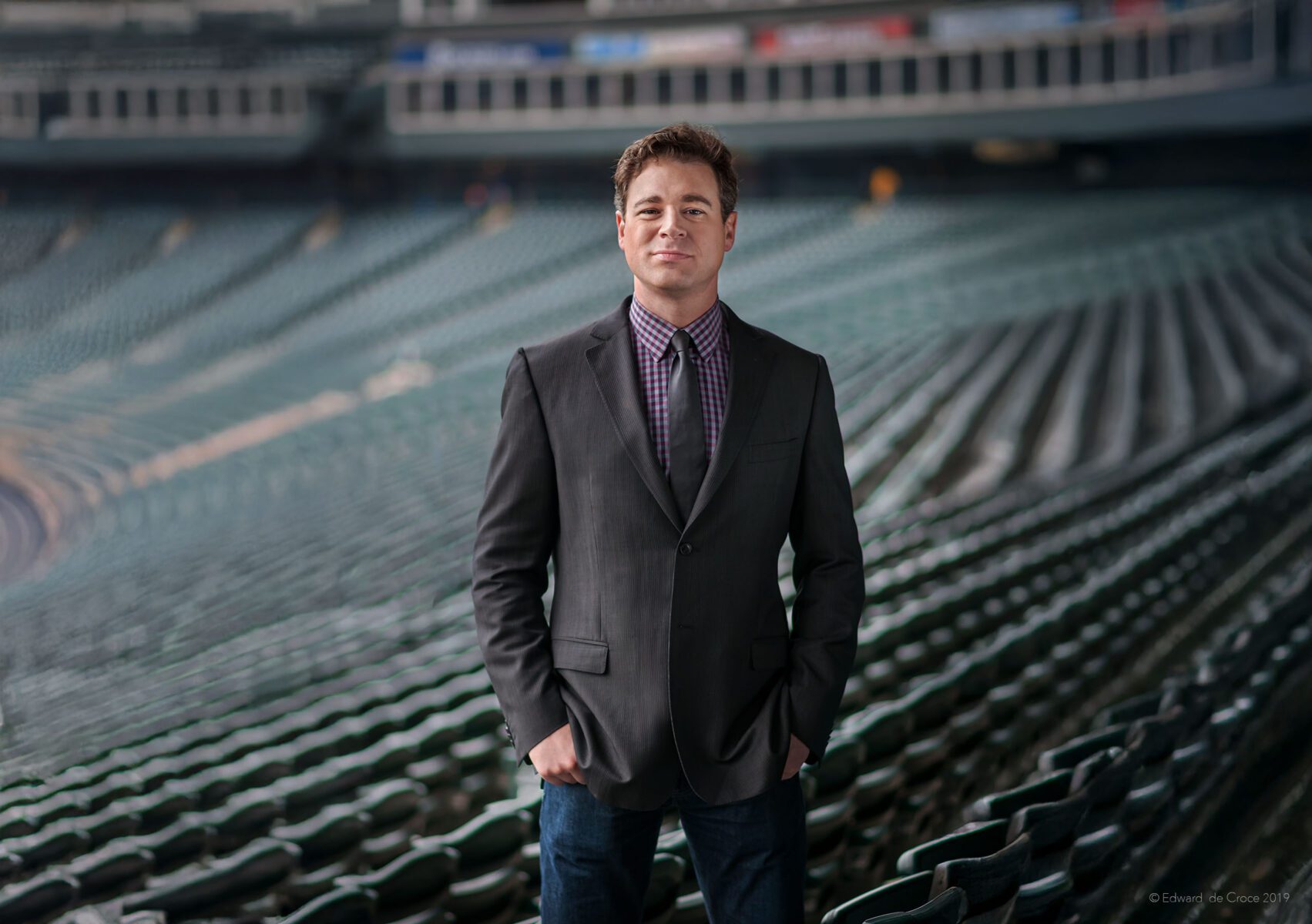 In Denver's Coors Baseball field, Colorado commercial portrait photographer, Edward C. DeCroce portrayed portrayed this story-telling photograph of sports writer Jonah Keri.